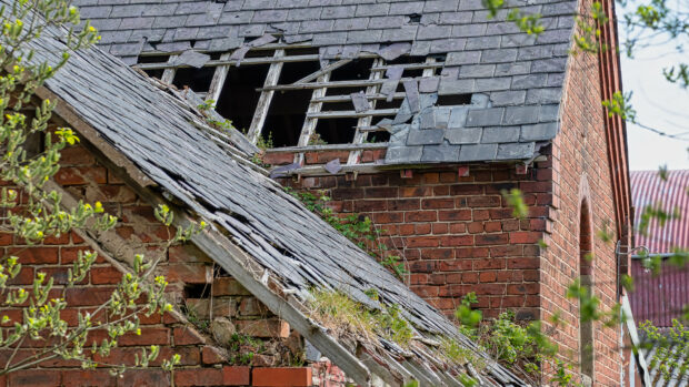 Damaged slate roof tiles on a pitched roof.